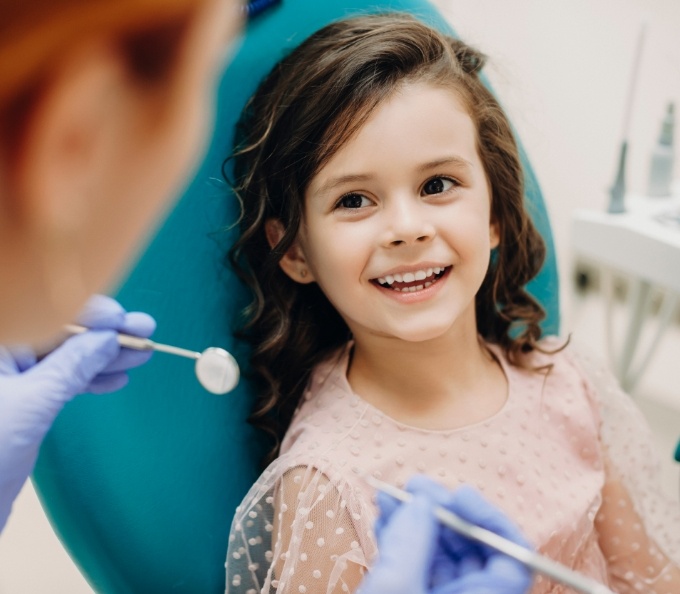 Young girl in dental chair smiling at her pediatric dentist