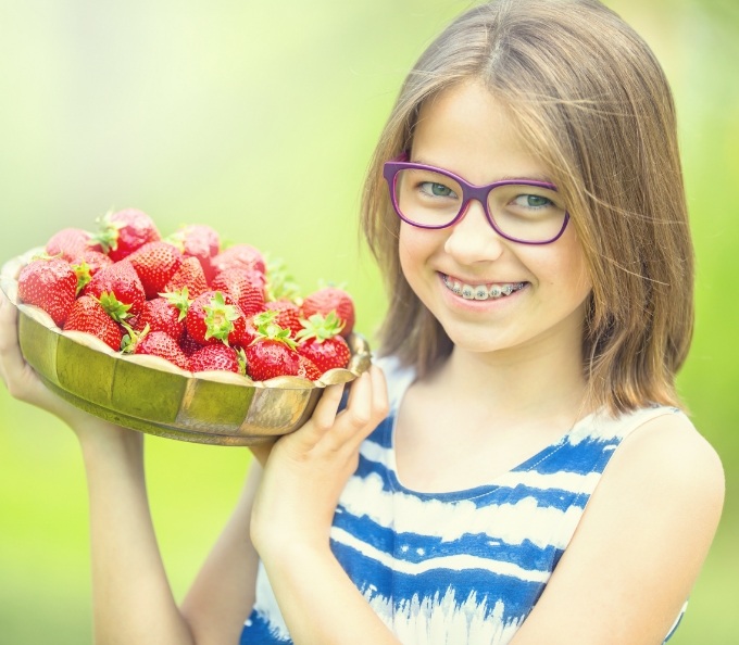 Smiling girl holding basket of strawberries