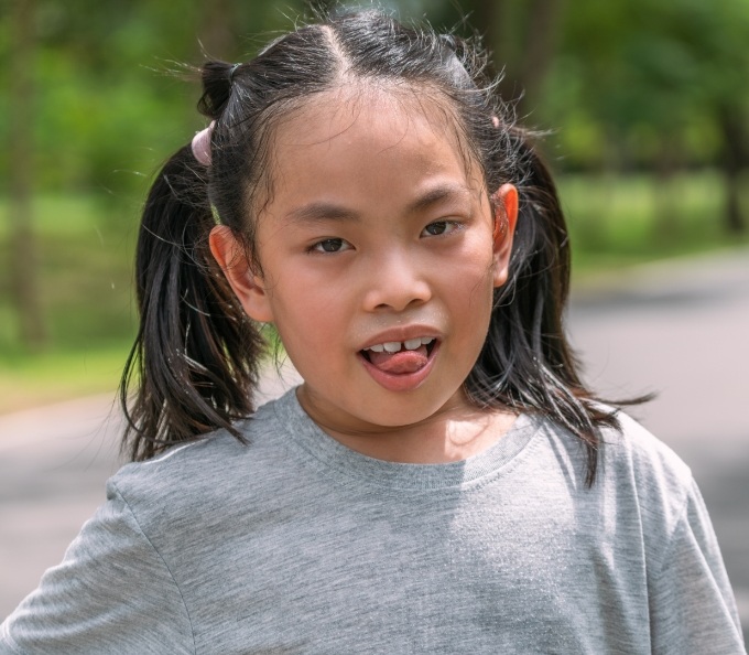 Young girl with small gap between front teeth sticking her tongue out