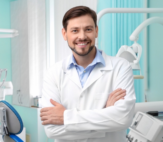 Doctor in white lab coat smiling in dental treatment room