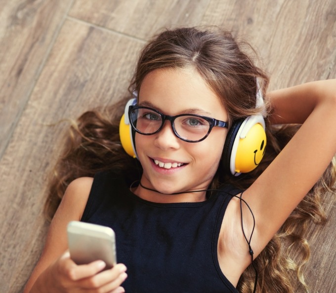 Young girl laying on floor and listening to music with headphones