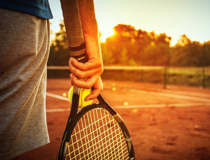 Person on tennis court at sunset