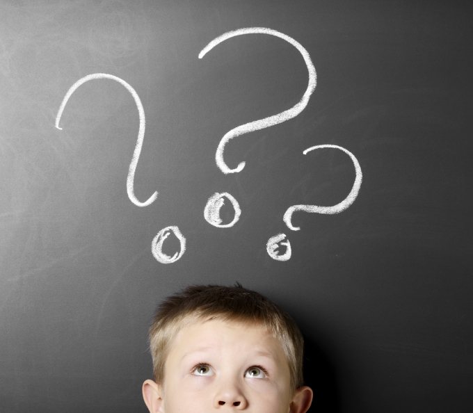 Young boy looking thoughtful with question marks above his head