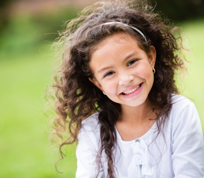 Young girl with curly hair smiling outdoors